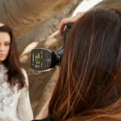 Fotografka z zimną stopką na aparacie celuje w modelkę w białej sukni.